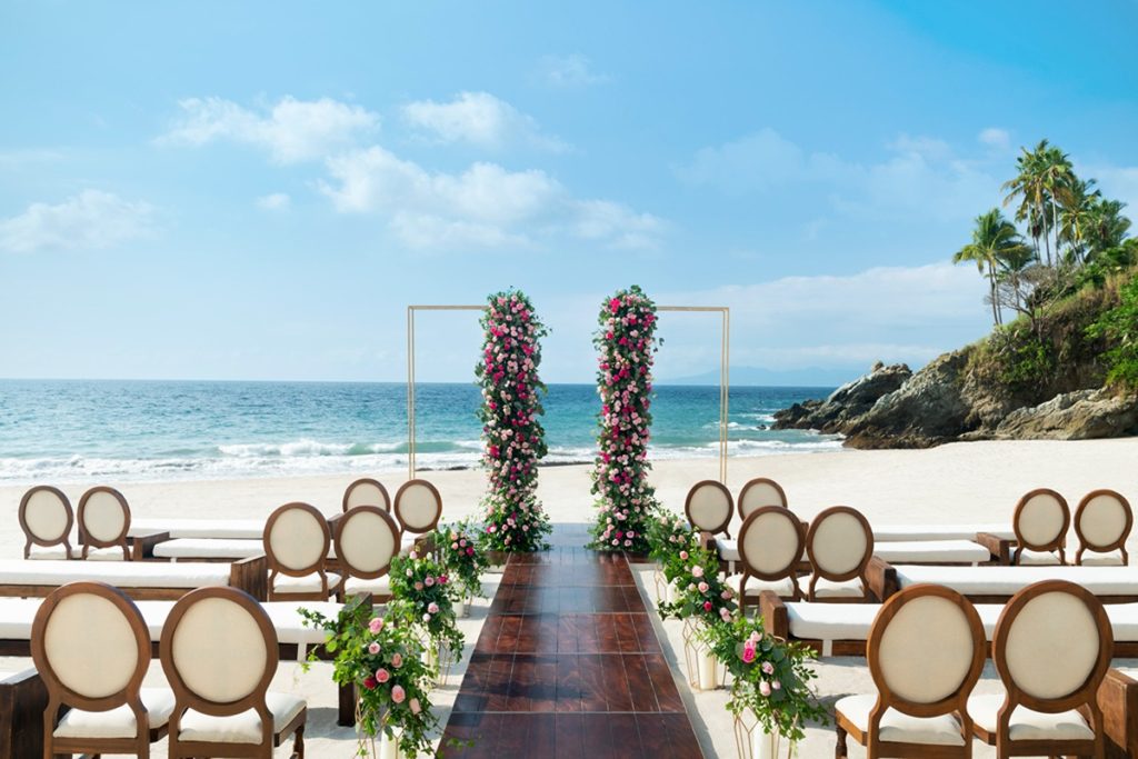 wedding with wooden aisle and wooden chairs at the beach shore
