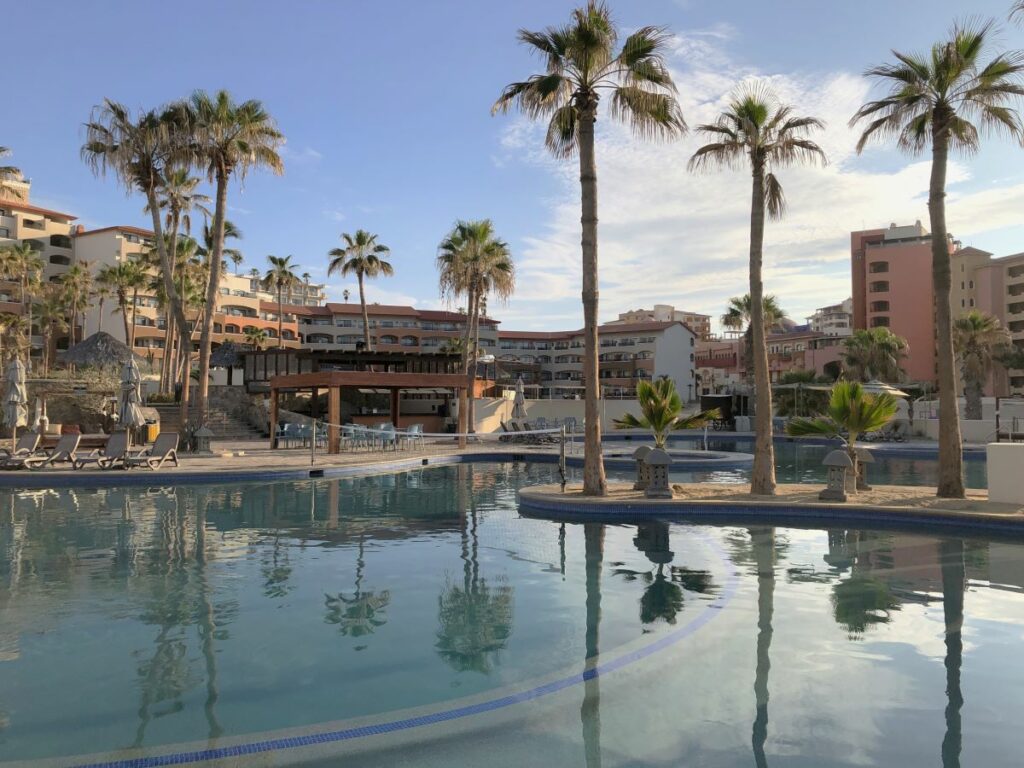 Hotel pool area with palmtrees and room buildings at the back