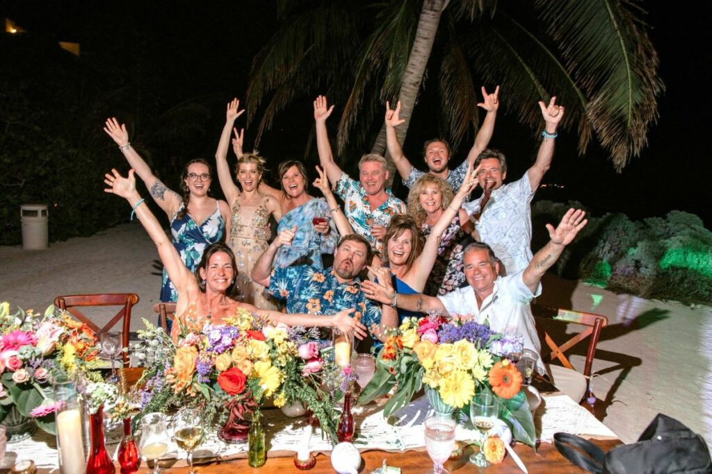 Wedding guests posing for a pic, cheering with their drinks and arms up