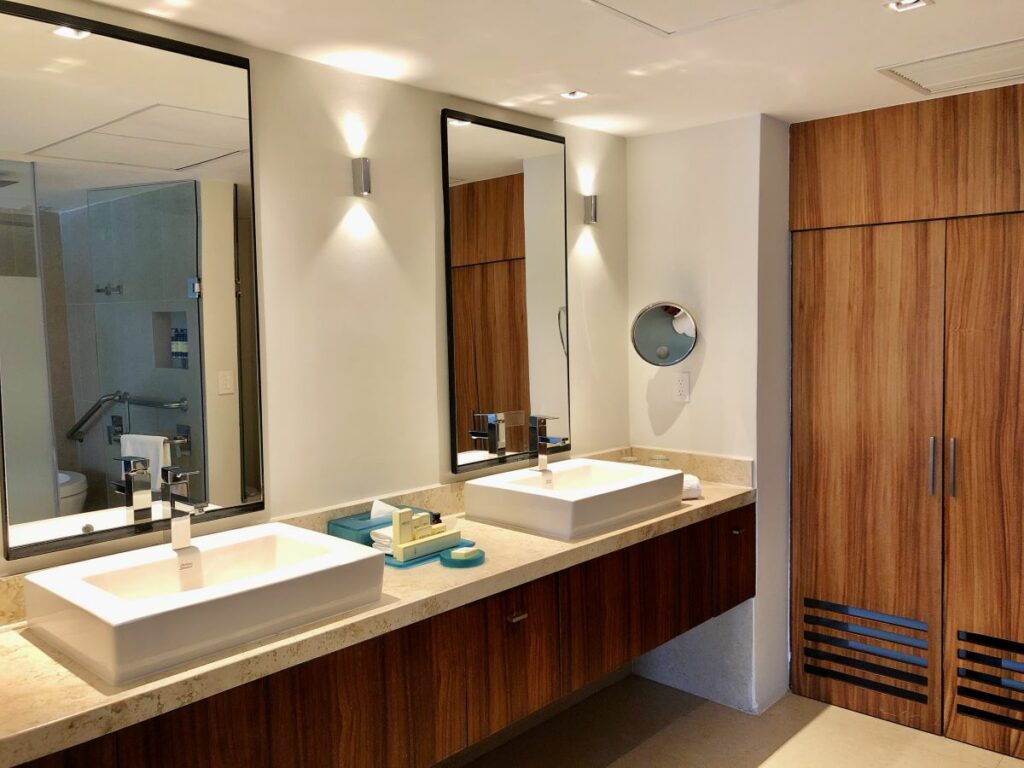 hotel bathroom with double vanities with large mirrors and wooden closet