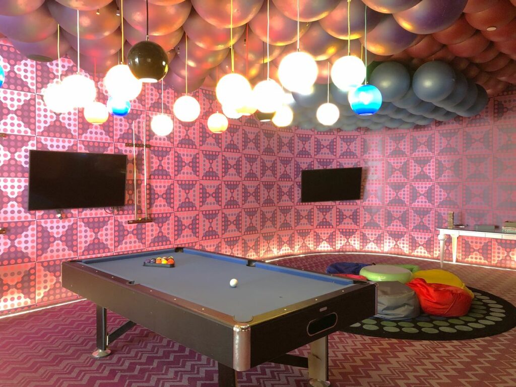game room with a pool table, screens, couches and hanging lanterns