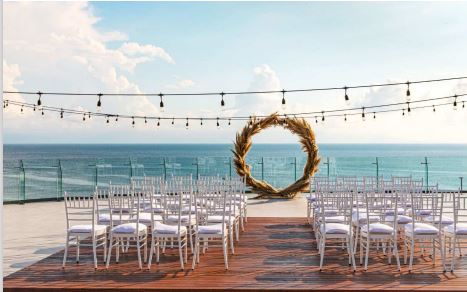 Destination wedding ceremony set-up with white tiffany chairs, circular arch and string lights at the Terraza presidential suite of the Dreams Bahia Mita