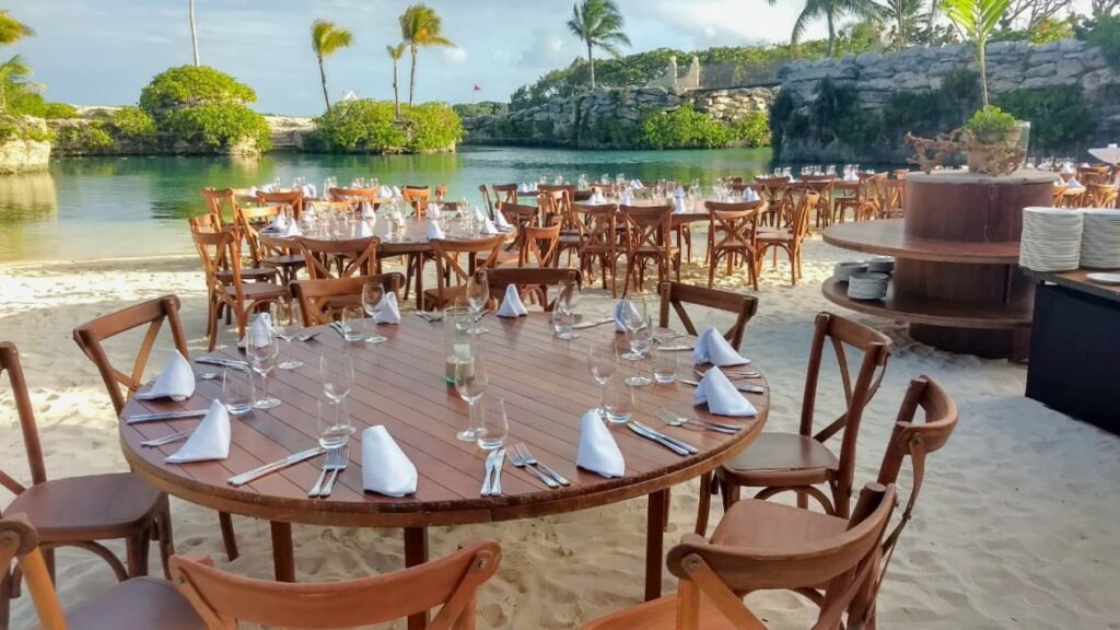 Wedding set up at the beach with wooden round tables and wooden chairs