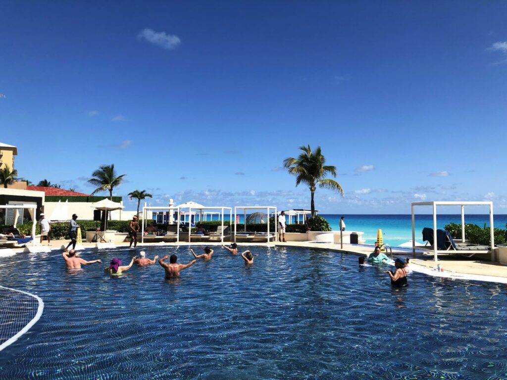 resort pool with ocean view and guests doing acuating excercise
