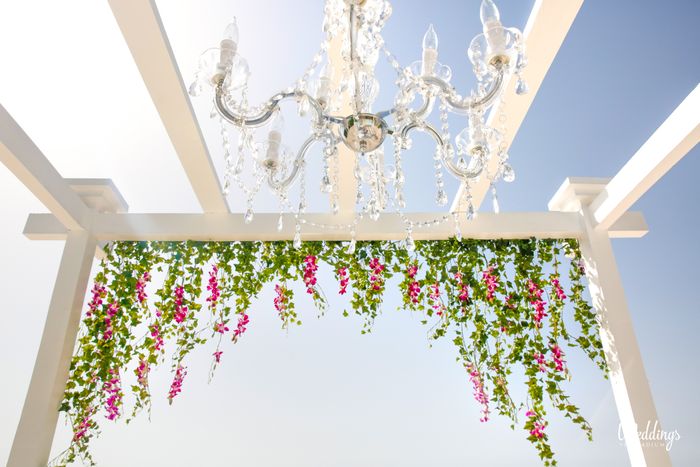 wedding pergola with hanging leaves and flowers with a crystal chandelier