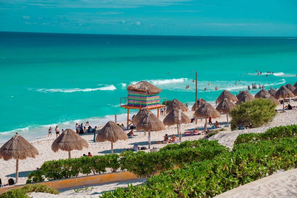 a public beach in cancun with palapa roofs and beautiful clear waters