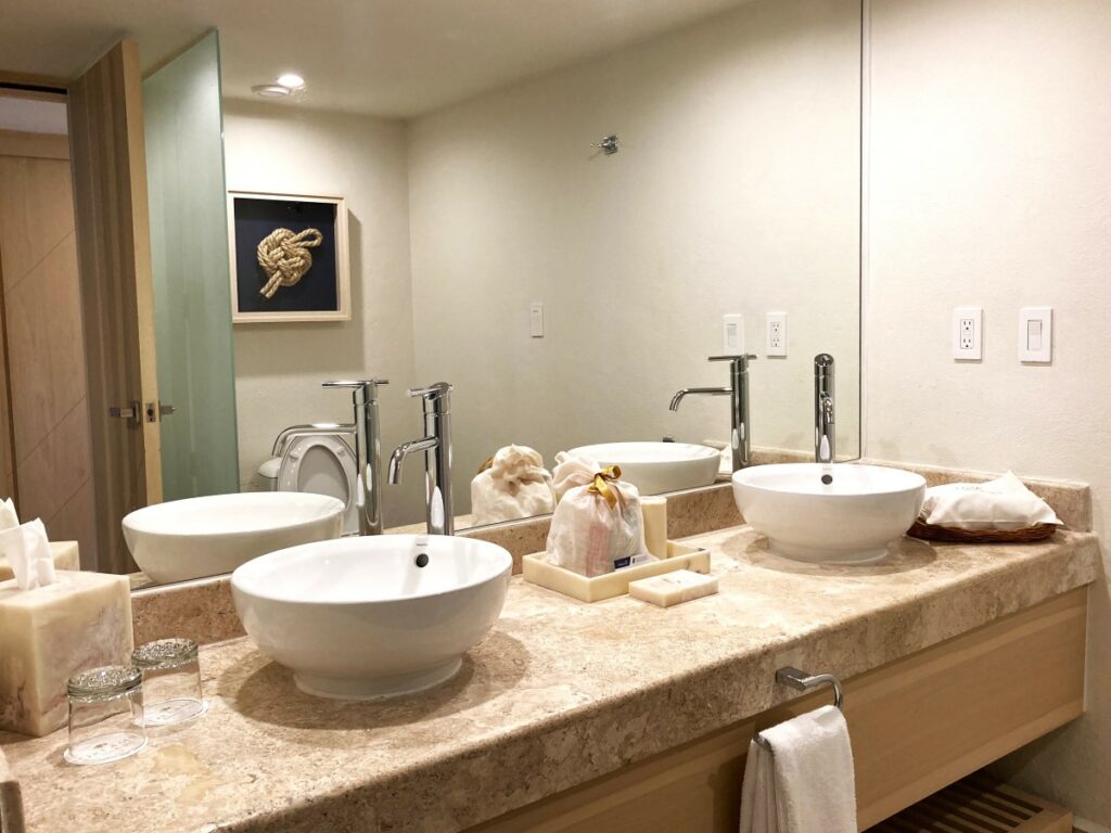 hotel suite bathroom with a large mirror, two double sinks and bathroom amenities