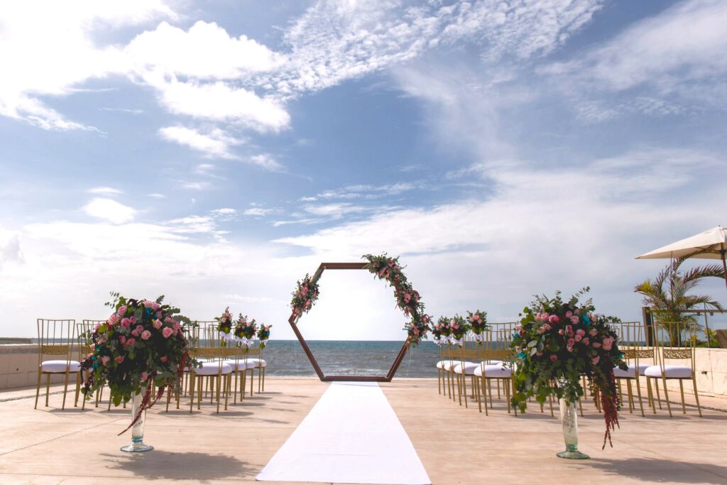 a wedding ceremony set up on an ocean front terrace with an hexagon with flowers