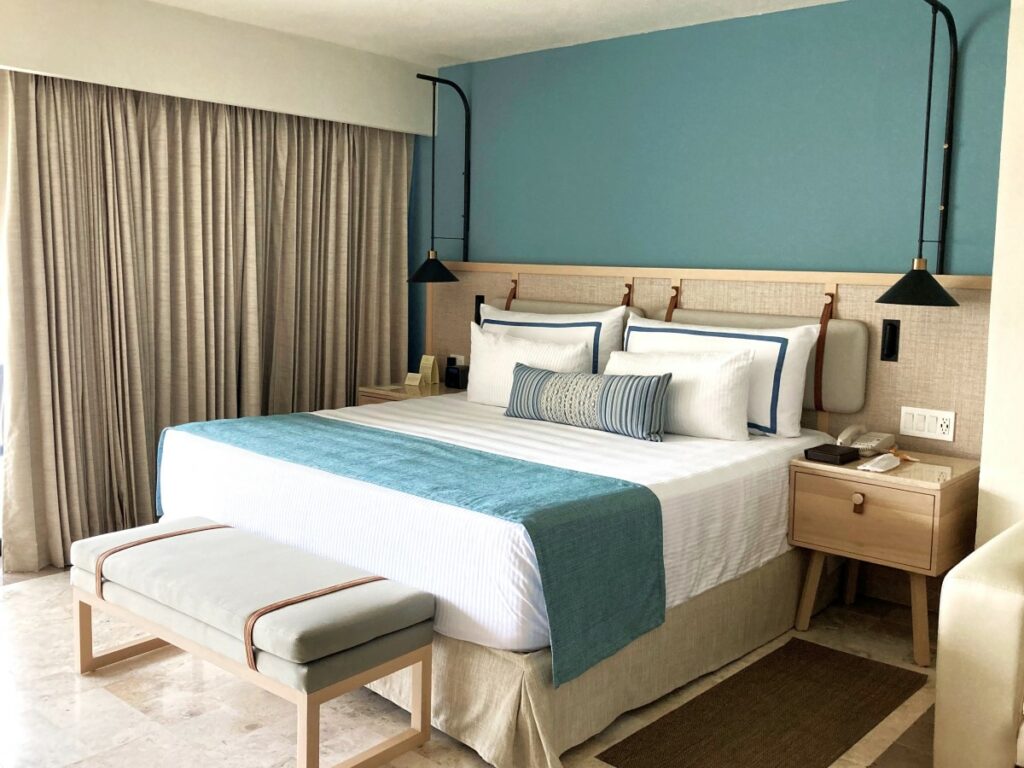 hotel room with a king size bed decorated in turquoise and beige colors
