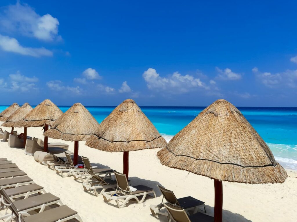 beach area with palapas and lounge chairs at a beach resort in cancun