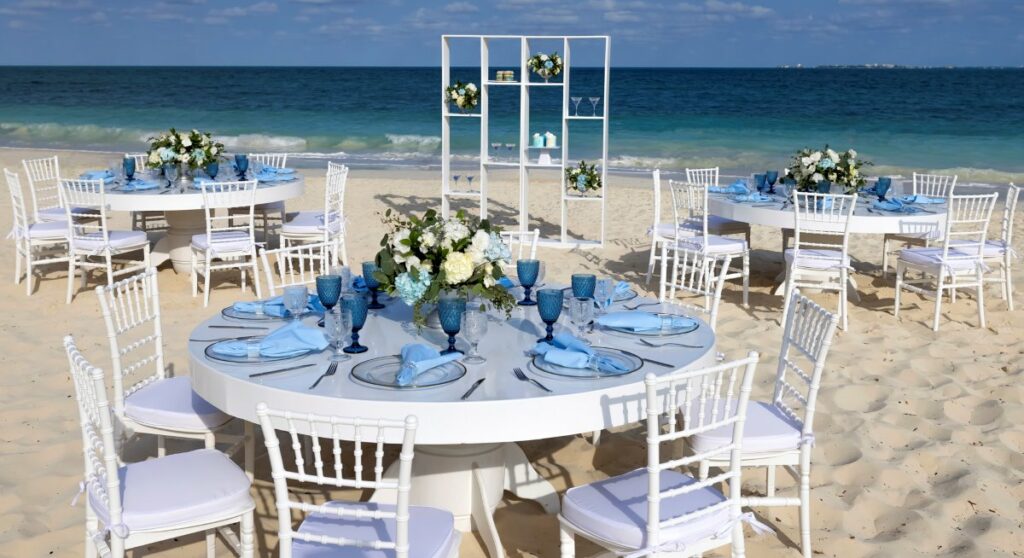 Beach wedding reception all in white with blue elements and white flower centerpieces