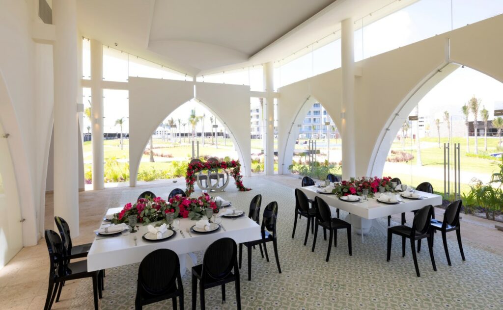 Elegant indoor wedding reception with black and white furniture and red flower arrangements