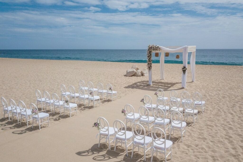 Elegant beach wedding set up in Los Cabos with a white gazebo and white chairs 