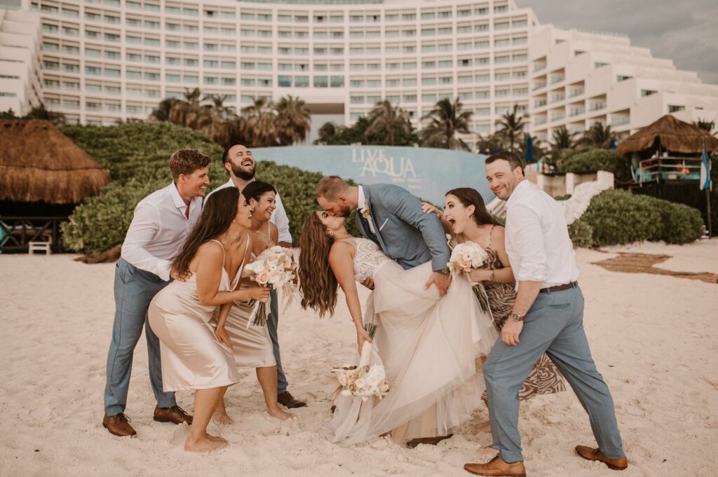 just married couple kissing surrounded by the bridal party at live aqua cancun beach wedding resort