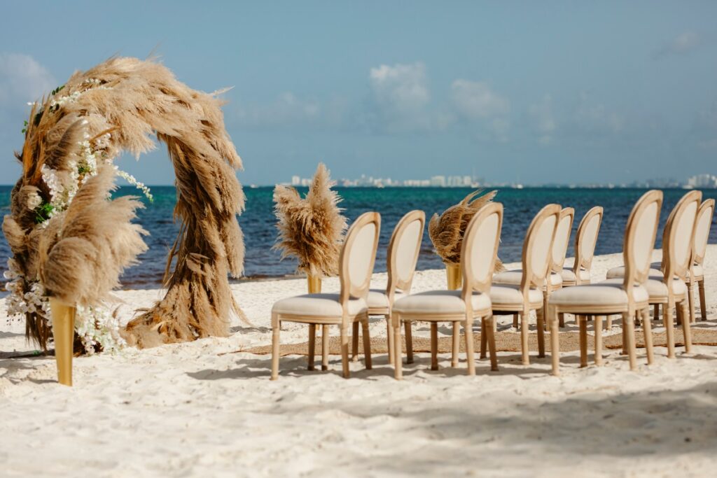 a beautiful beach wedding ceremony set up with an arch with pampas