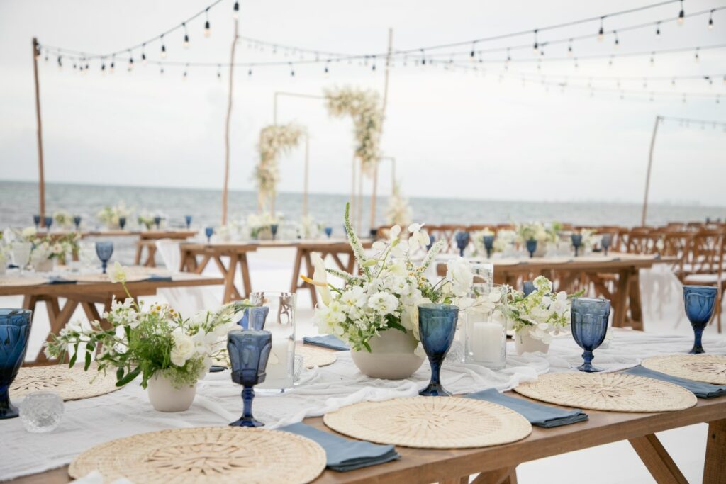 beach wedding set up with wooden furniture and white flowers