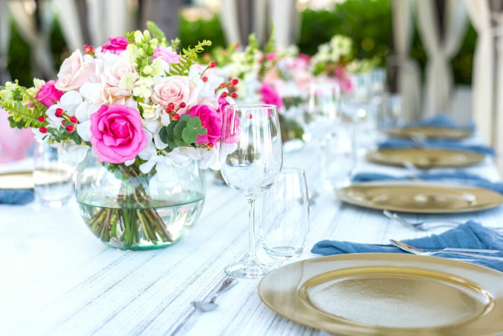 wedding reception table setup with white linens and rose flower centerpieces